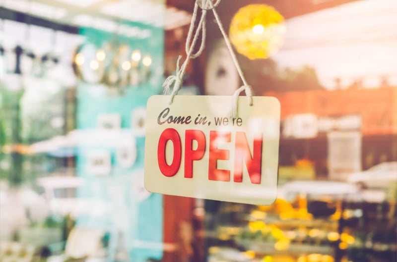 Open sign hanging on store door with blurred shop interior behind